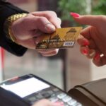 Man reikt een gouden creditcard aan een vrouw bij een betaalautomaat, focus op lokaal afrekenen