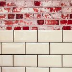 Witte glanzende metro tegels op wand met daarboven een klassieke bakstenen muur