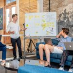 Team bespreekt projectvoortgang en technische uitwerking bij een whiteboard met post-its in creatieve werkomgeving