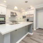 Strakke moderne keuken met wit werkblad, grijze accenten en RVS inbouwapparatuur voor een luxe uitstraling