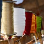 Rij gekleurde garenklossen in diverse tinten zoals blauw, wit, rood en groen in een stoffeeratelier