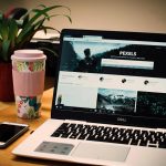 Open laptop met snelle website op scherm, naast smartphone en koffiebeker op een houten bureau