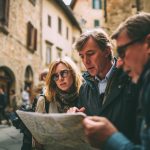 Reizigers bekijken samen een stadskaart tijdens een groepsreis Zuid-Europa door een historische binnenstad.