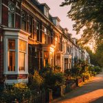 Rij verzorgde herenhuizen met nette gevels aan een schaduwrijke straat tijdens zonsondergang